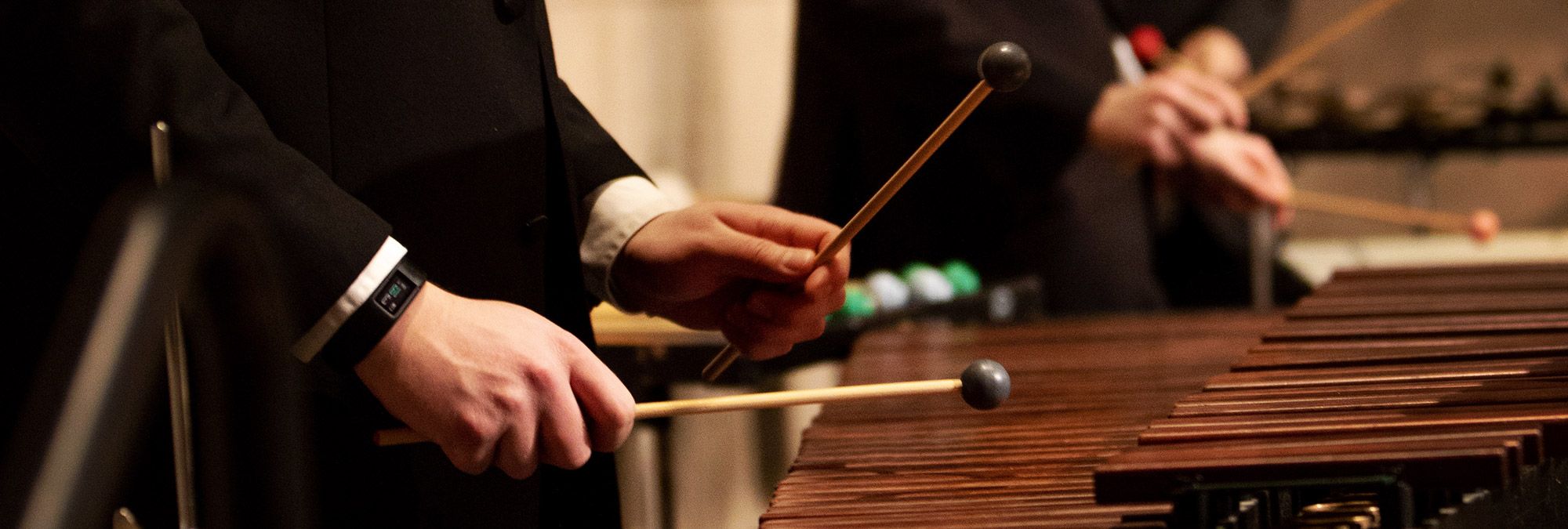 A percussionist's hands holding mallets and playing the marimba