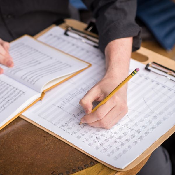 a student sits at a desk writing notes on a score