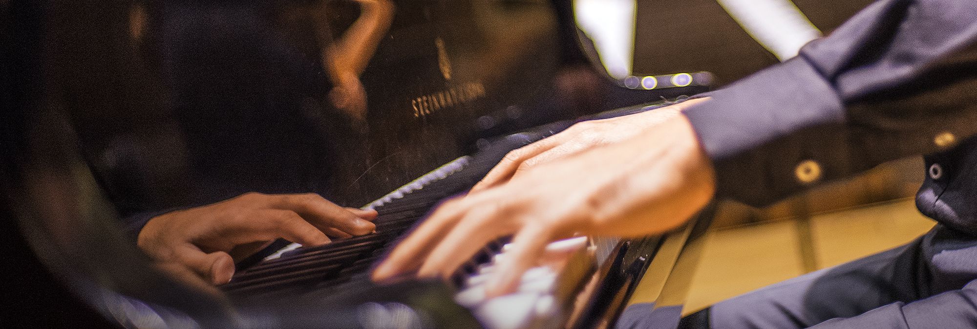  close picture of hands on the keys of a Steinway Piano