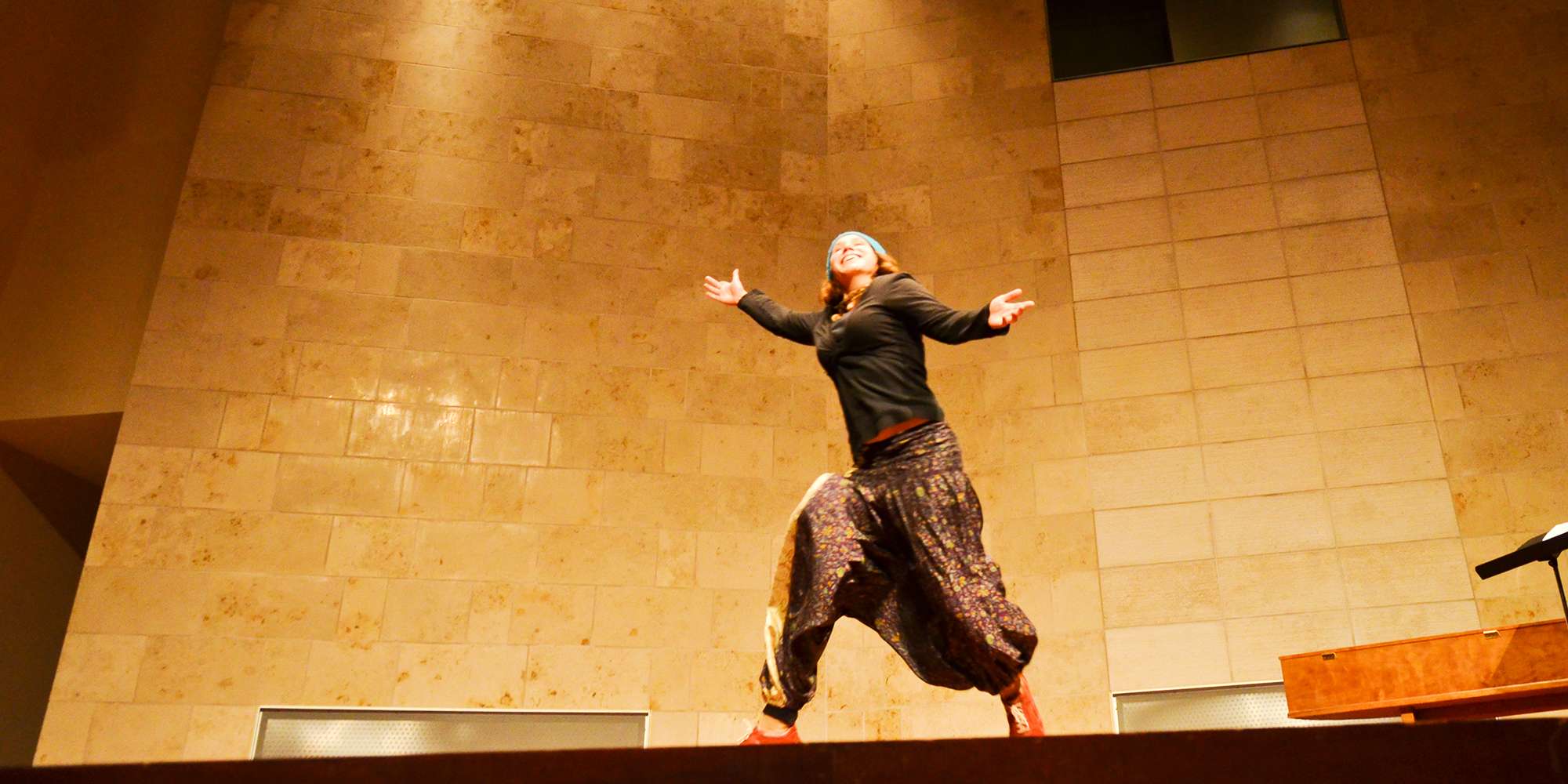 person with a dramatic, dynamic pose on the recital hall stage