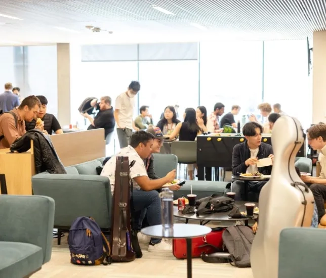 a lively lounge in the bowes center with students eating and talking
