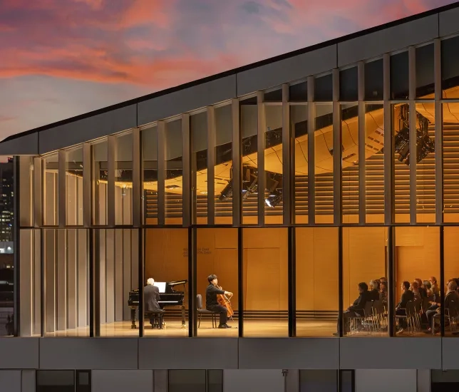 Bowes Center from the outside at dusk, with a performance visible through the windows.