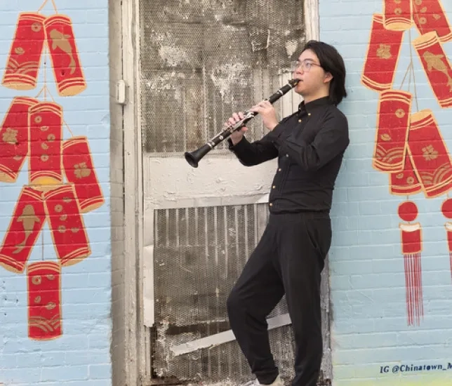 Student playing clarinet in front of mural