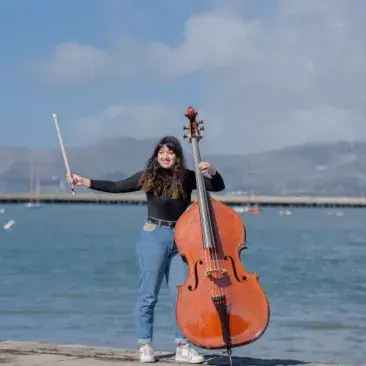 a bassist holds a bass at the pier