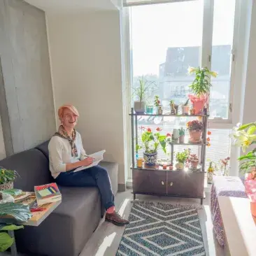 a student sits in their dorm room surrounded by plants