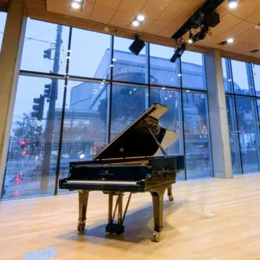 a piano in cha with symphony hall through the window behind it
