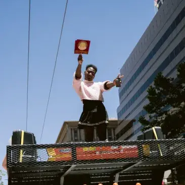 a student holds up a sfcm pride sign on a float