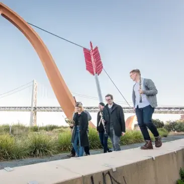 students walk in front of the bow and arrow sculpture around the embarcadero