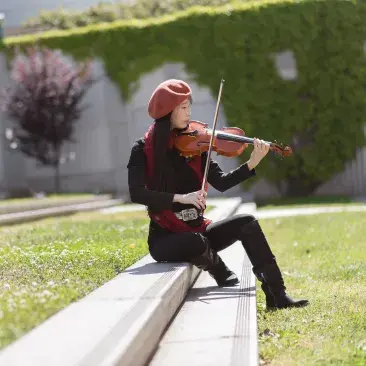 violinist sits in stairs playing the violin outside