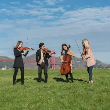 string quartet stands and laughs in a park with the golden gate in the background