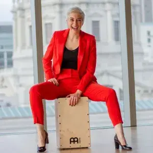 amelie anna hinman sits on hand percussion and laughs while playing