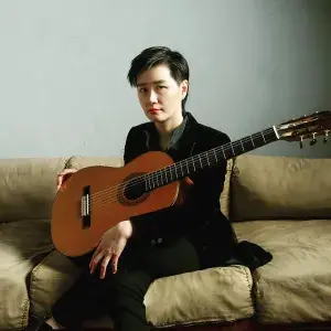 Meng Su headshot while holding guitar