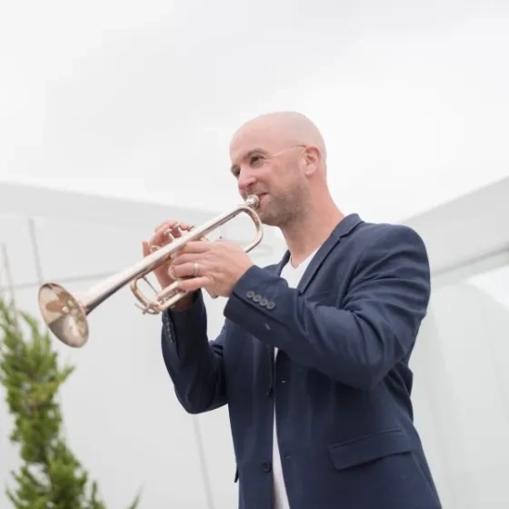 Adam Luftman playing the trumpet on the roof of the Bowes Building