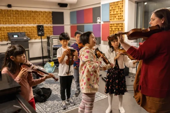 a group of pre-college violinists watching a teacher