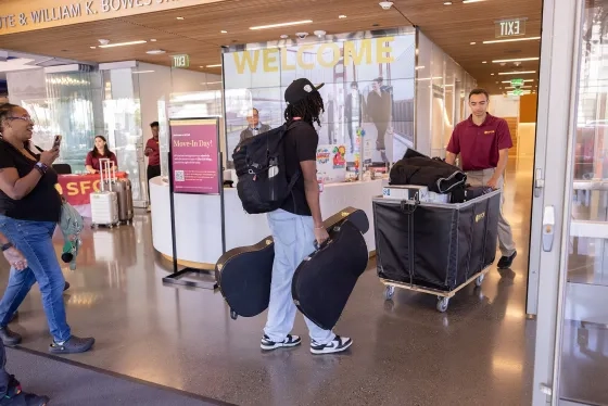 A Resident Advisor helps a student move into the Bowes Center. 