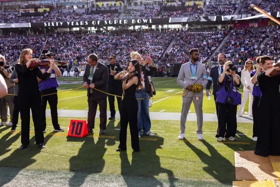 SFCM students play in a line as football stars enter the field. 