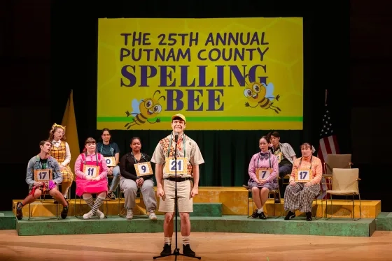 Student Seth Hanson (center) performs as speller Chip Tolentino.