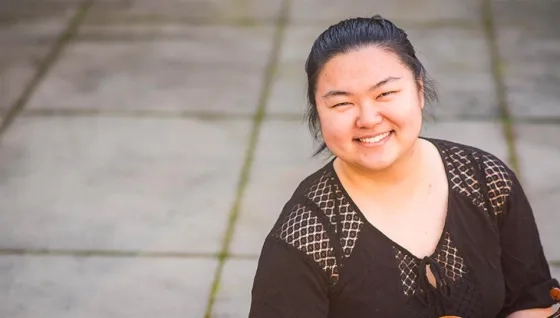 smiling student holding string instrument