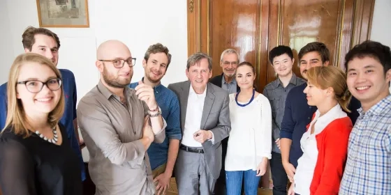 students and professor take a group photo in Hamburg sunny indoor hallway in front of wooden door