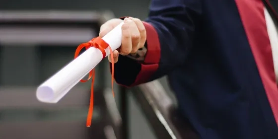 Person holding white commencement scroll