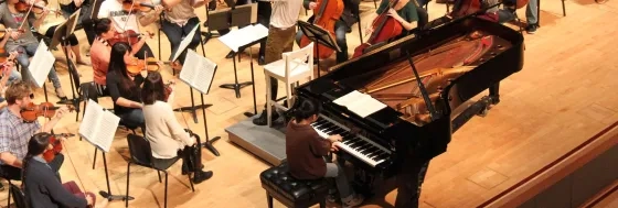 overhead shot of a pianist at a keyboard during an orchestra rehearsal