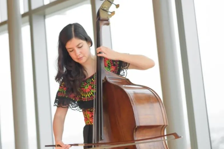 a double bassist plays in front of the windows of osher recital hall