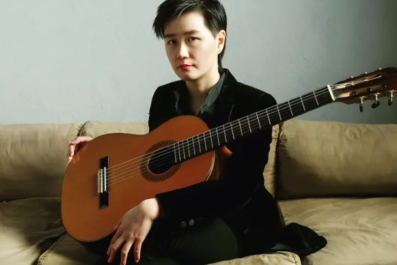 Meng Su headshot while holding guitar