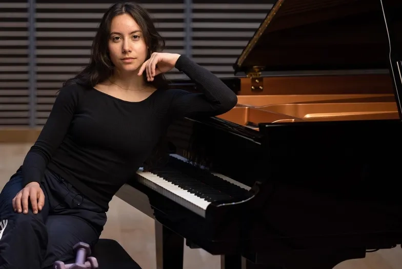 Raquel Fisk at the piano with a set of weights on the bench as well