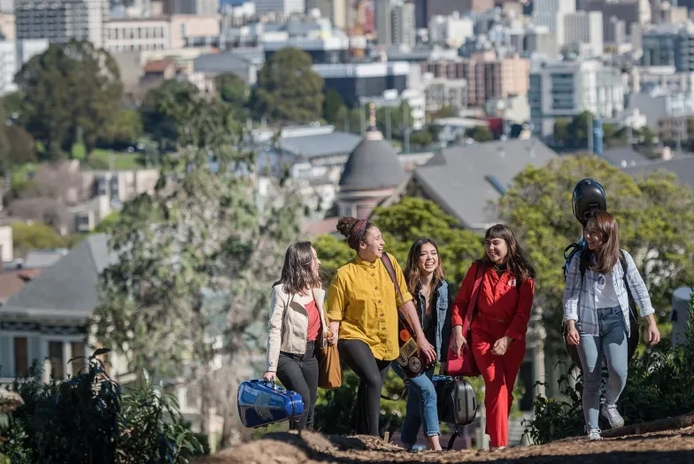 sfcm students walk through a park with their instrument cases