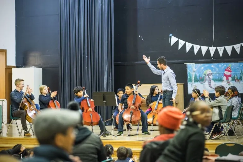 a teacher works with an orchestra on stage