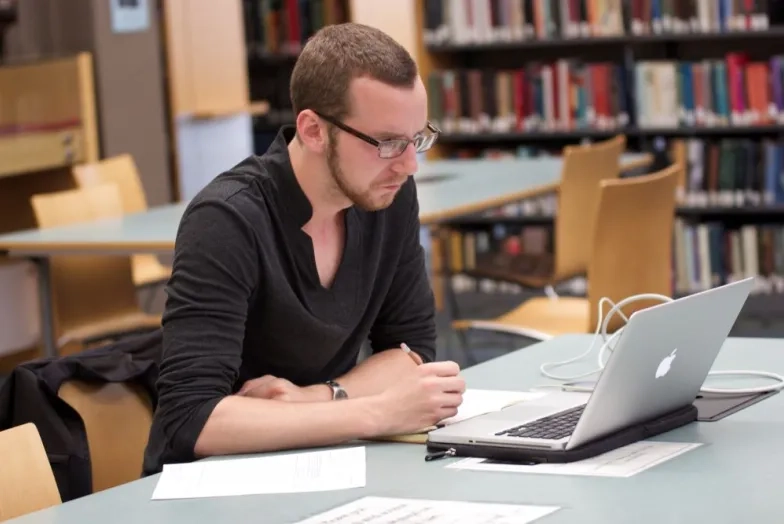 a student sits at their laptop in the library