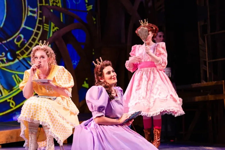 Three singers sing during an opera, they are dressed in gowns