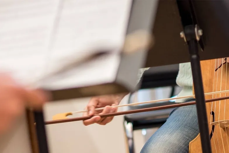 a student playing a historical bowed instrument