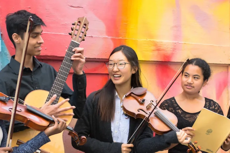 Pre college Photoshoot in Hickory Alley. Students are holding their instruments and smiling