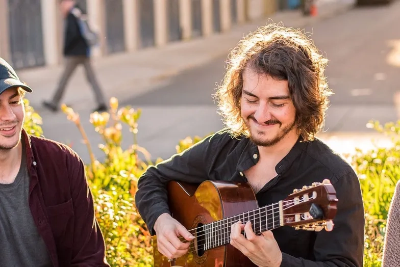 Student Life: three SFCM students, one playing guitar, sit outside together