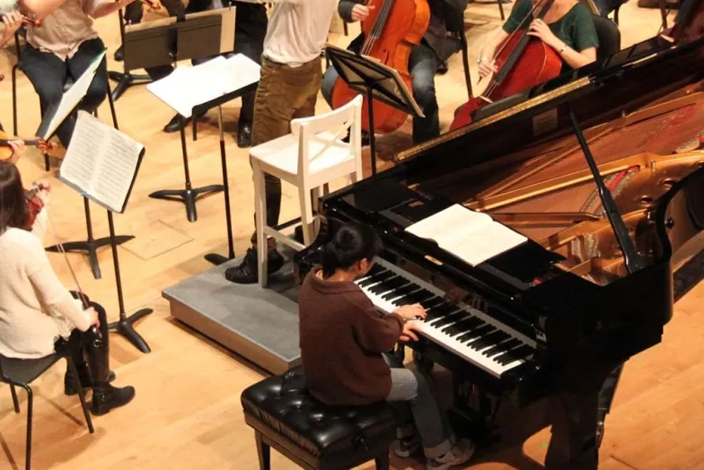 overhead shot of a pianist at a keyboard during an orchestra rehearsal