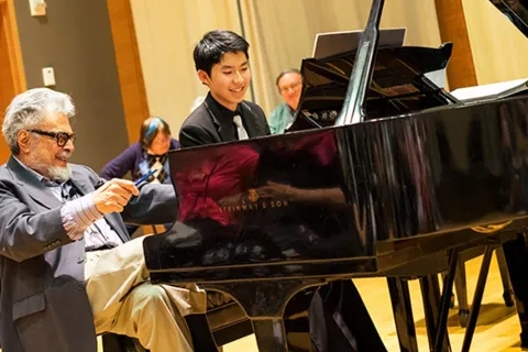 Piano student receiving lesson from professor in Osher Salon at 50 Oak St. Campus