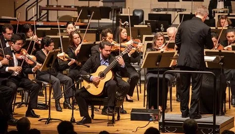 Solo guitarist plays in the front of an orchestra Winter term