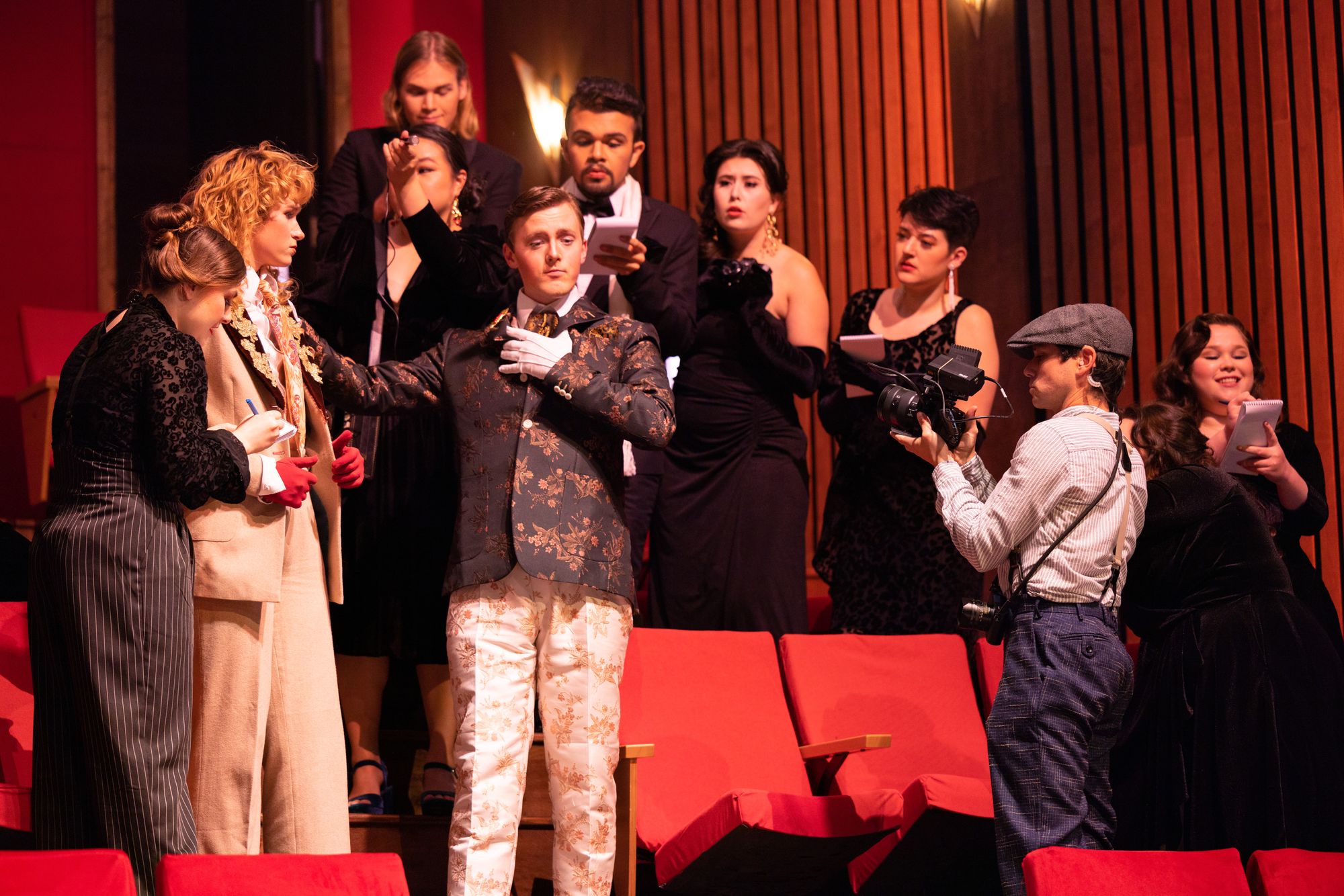 A dramatic Opera scene. Performers are standing in what looks like a theater, shocked at something